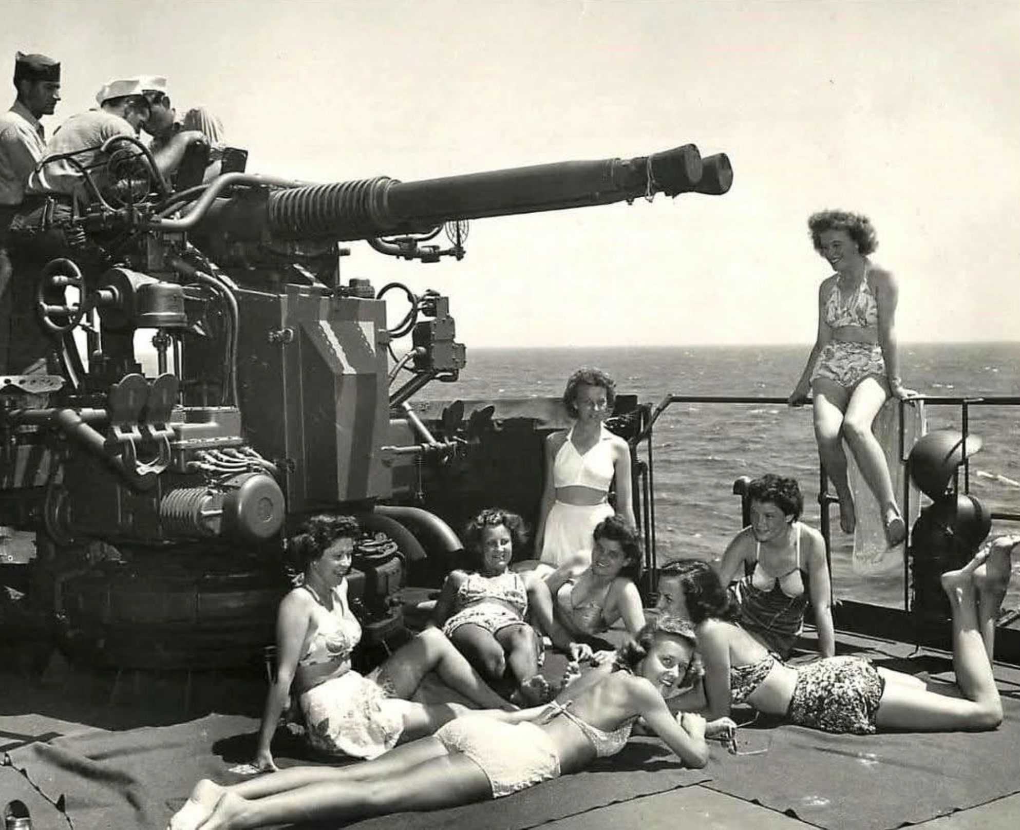 Army nurses soak up the sun next to a twin Bofors 40 mm gun aboard a US Coast Guard troop ship returning from Europe, 1945 